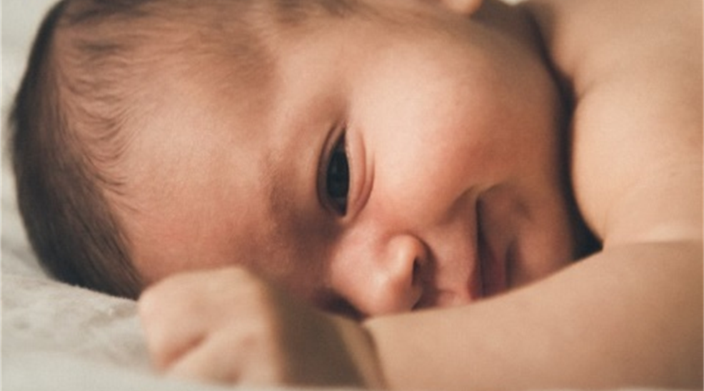 Smiling baby glimpsing first life.